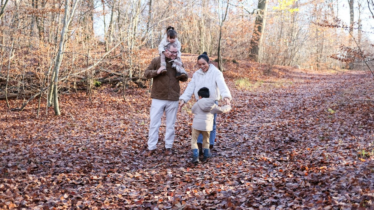 Family walking on a leaf-covered path in autumn woods
